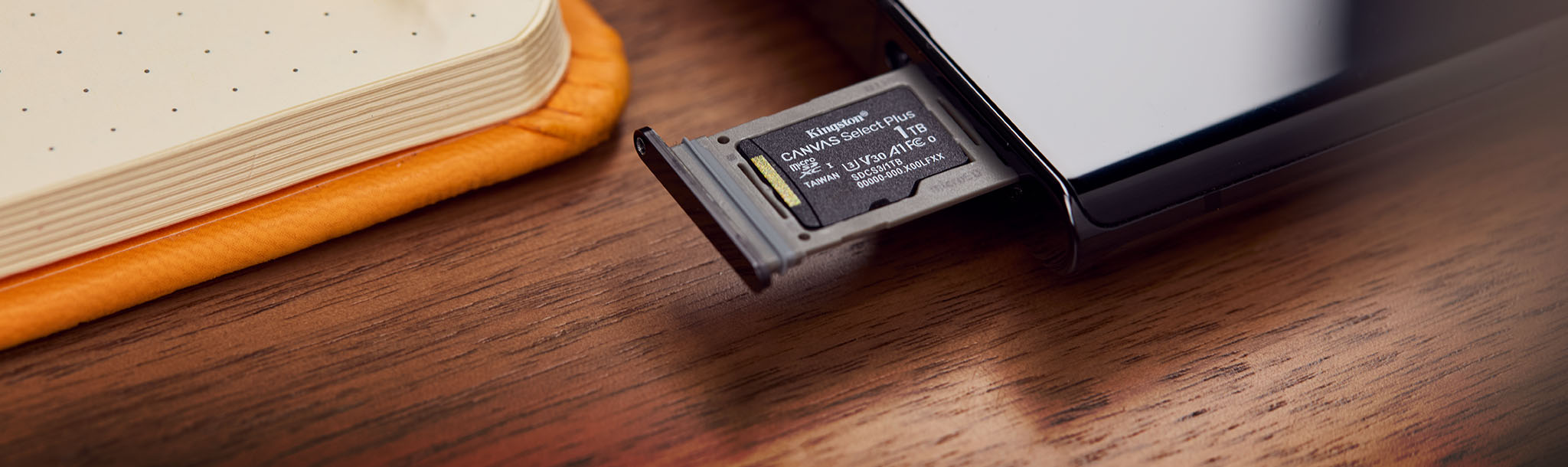 A 1TB Canvas Select Plus microSD sits in a tray ejected from a mobile device