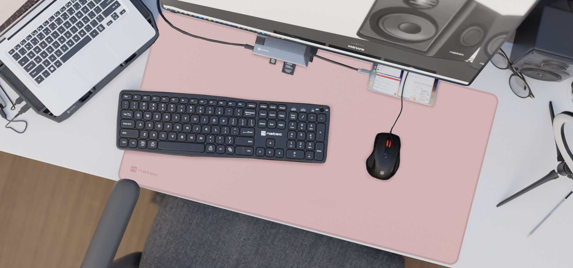 Aranjament de birou cu un mouse pad roz pal, cu o tastatura neagra, mouse si difuzoare pentru computer