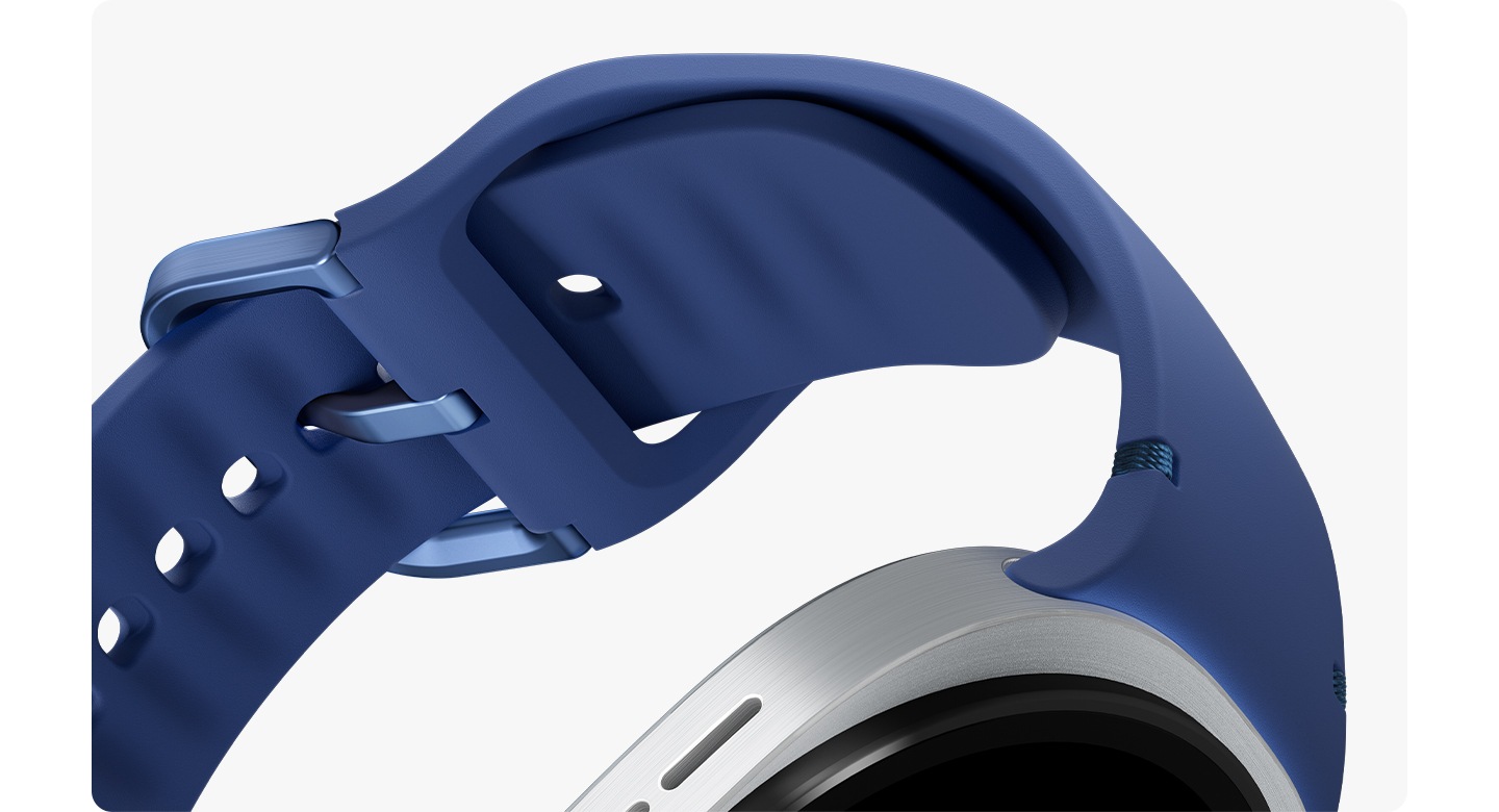 A tilted, close-up shot of the soft, rubber material on a Blue Galaxy Watch8 Sport Band, which is attached to Galaxy Watch8 and buckled to form a closed loop.
