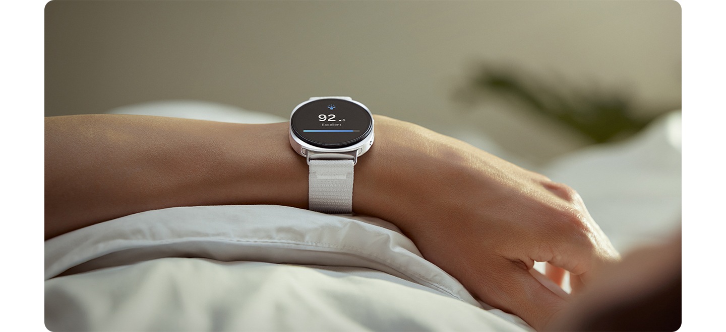 A person wearing Galaxy Watch8 with a White Galaxy Watch8 Fabric Band has their arm over the covers of their bed.