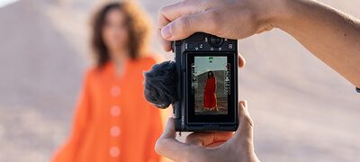 Imagine de utilizare cu maini tinand camera vertical si fotografiind un model, vizibila pe ecranul camerei