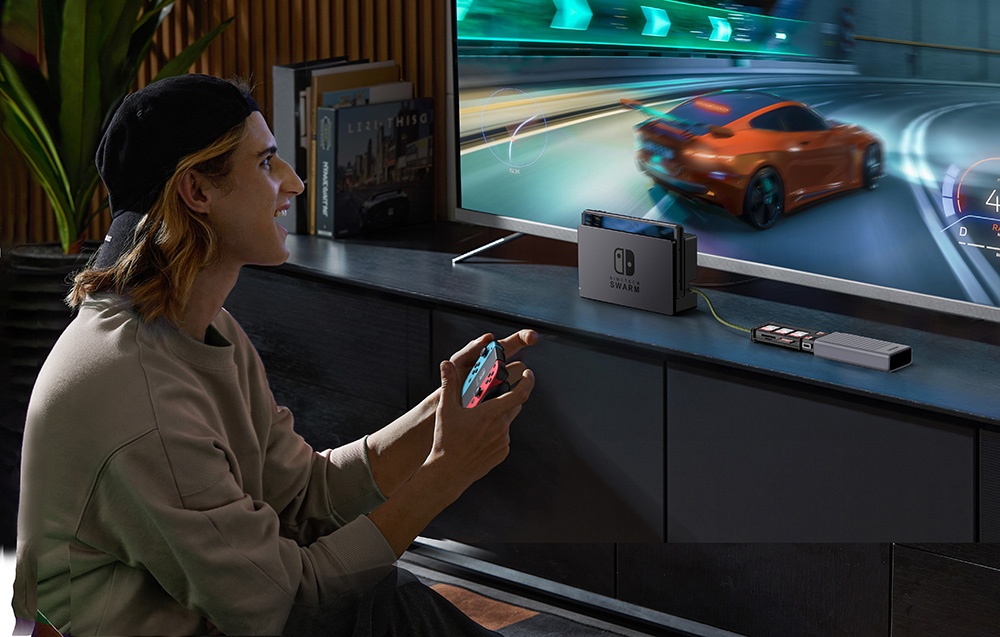 Un bărbat joacă pe o consolă Nintendo Switch conectată la televizor, ținând un controler