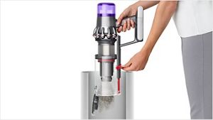 O femeie golind aspiratorul Dyson V11™ intr-un cos de gunoi